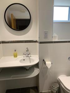 a white bathroom with a sink and a mirror at The Apartment Boscawen Woods in Truro