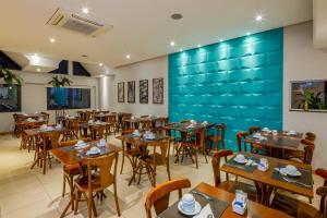 a restaurant with wooden tables and chairs and a blue wall at Hotel Laghetto Viale in Gramado