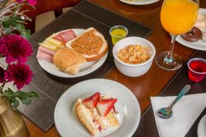 a table with plates of breakfast foods and orange juice at Hotel Laghetto Viale in Gramado