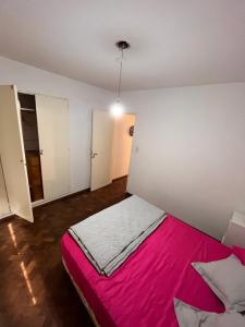 1 dormitorio con 1 cama con manta rosa en Hermoso departamento céntrico de dos ambientes. en Rosario