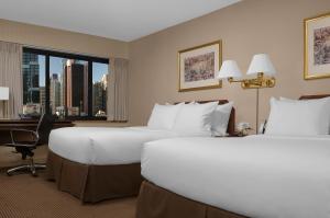 a hotel room with two beds and a desk and a window at The Manhattan at Times Square in New York