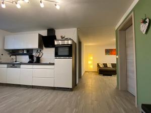 uma cozinha com armários brancos e uma sala de estar em Hempis Ferienwohnungen em Hochkirch