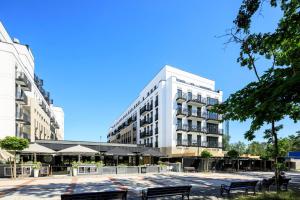duży biały budynek z ławkami przed nim w obiekcie VacationClub - Baltic Park Fort Apartament G.405 w Świnoujściu