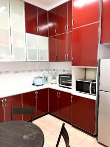 a kitchen with red cabinets and a table in it at Muar Homestay [Located at Sabak Awor Seafood Court] in Muar