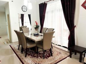 comedor con mesa, sillas y reloj en Muar Homestay [Located at Sabak Awor Seafood Court], en Muar