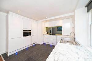 una cocina con armarios blancos y fregadero en The Shore Apartment en Queensferry