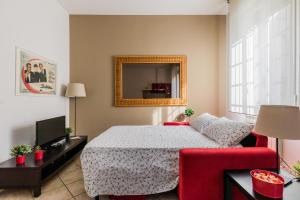 a bedroom with a bed and a red chair and a mirror at Portobello Apartments in Bologna