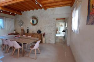 a kitchen and dining room with a wooden table and chairs at Grande maison , jardin,flipper,babyfoot, ping pong, 1 km mer, proche golf, Port en Bessin, Bayeux et plages du débarquement, adaptée enfants in Commes
