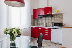 una cucina con armadi rossi e un tavolo in vetro con fiori di Portobello Apartments a Bologna