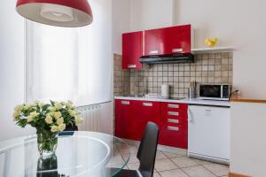 kuchnia z czerwonymi szafkami i szklanym stołem z kwiatami w obiekcie Portobello Apartments w Bolonii +37 zdjęć