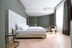- une chambre avec un grand lit blanc et une table dans l'établissement Palazzo Froussard B&B and Living, à Lucques