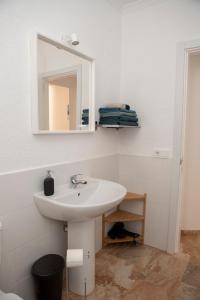 une salle de bains blanche avec un lavabo et un miroir dans l'établissement Palmera, à Agüimes