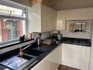 a kitchen with white cabinets and a sink and a window at Shared house on Lakewood crescent in Bristol