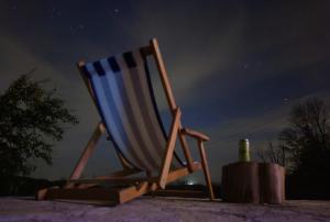 a beach chair and a bottle of wine at night at Rudnički Eko Breg in Rudnik Kačerski