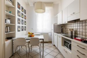 kuchnia z białymi szafkami, stołem i krzesłami w obiekcie Portobello Apartments w Bolonii
