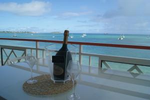 een fles wijn zittend op een tafel met twee glazen bij Grand Studio « Blue Sunset » mer, plage, piscine. in Marigot