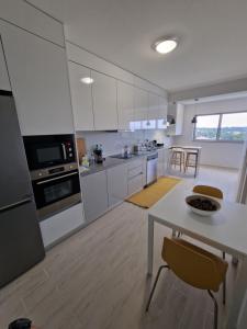 a kitchen with white cabinets and a table and chairs at Piso Panorama in Oliveira do Bairro