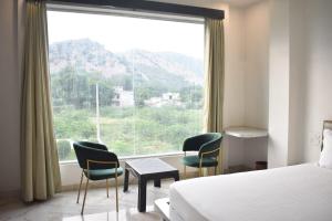 una camera d'albergo con un letto e sedie e una grande finestra di Hotel celebration a Alwar
