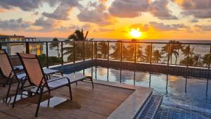 a balcony with a view of the ocean at sunset at Porto de Galinhas PORTO EXCLUSIVE BY AFT in Porto De Galinhas