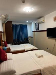 a hotel room with three beds and a television at Hoàng Anh Hotel in Ho Chi Minh City