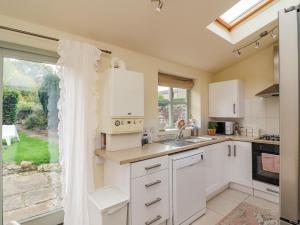 a kitchen with white cabinets and a large window at Pheasant Cottage in Oakham