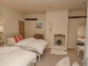 two beds in a room with a fireplace at Pheasant Cottage in Oakham