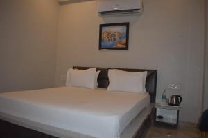 łóżko z białą pościelą i poduszkami w pokoju w obiekcie Hotel celebration w mieście Alwar