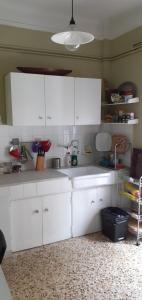 cocina con armarios blancos y fregadero blanco en Cozy Penthouse, en Tesalónica