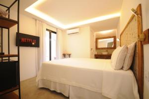 a bedroom with a white bed and a mirror at Villa Santa Fé in Búzios