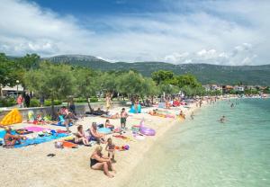 a group of people on a beach near the water at Apartments Bazina in Kaštela