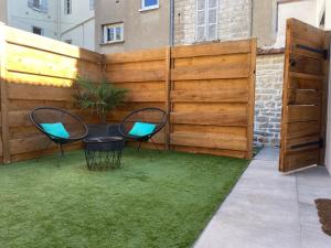 a patio with two chairs and a table in front of a fence at Les Jardins Secrets - Gare & Centre by Apparts Spa Dijon in Dijon