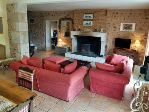 sala de estar con 2 sofás rojos y chimenea en Gîte Vitrac-Saint-Vincent, 4 pièces, 6 personnes - FR-1-653-132, en Montembœuf