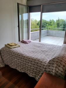 a bedroom with a bed and a large window at Chalet en Somió con finca independiente in Gijón