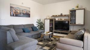 a living room with two couches and a flat screen tv at Apartments Bazina in Kaštela