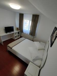 a bedroom with a large white bed and a television at "Apartament"-Casa Genius in Ploieşti