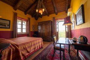 una camera con letto, scrivania e tavolo di Villa Bricco dei Cogni a La Morra