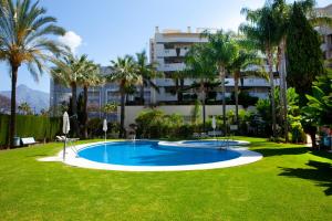 una piscina en un patio con palmeras y un edificio en Apartamento Puerto Banus, en Marbella