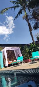 a pool with two chairs and a table and a tent at POUSADA MAORI Boiçucanga in Boicucanga