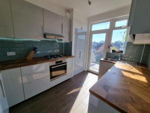 a kitchen with white cabinets and a large window at Lovely 2 bedroom flat in North West London in Hendon