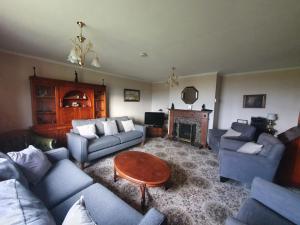 sala de estar con sofás, mesa y chimenea en Taigh Mairi Grimsay, en Carinish