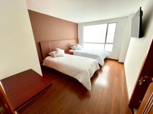 two beds in a room with a large window at HOTEL HOME in Pasto