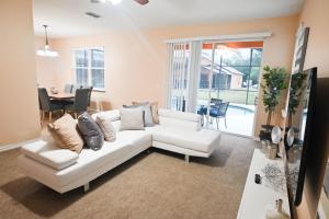 ein Wohnzimmer mit einem weißen Sofa und einem Tisch in der Unterkunft Disney Home + Private Pool in Davenport