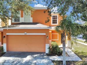 ein orangefarbenes Haus mit einer Garage und einer Palme in der Unterkunft Disney Home + Private Pool in Davenport