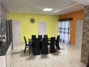 a dining room with a table and black chairs at Logement 2 chambres au sud de Mayotte in Bouéni