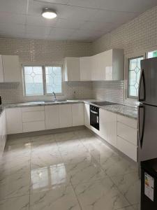 uma cozinha com armários brancos e um frigorífico preto em Logement 2 chambres au sud de Mayotte em Bouéni
