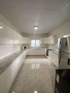 a large kitchen with white cabinets and a refrigerator at Logement 2 chambres au sud de Mayotte in Bouéni