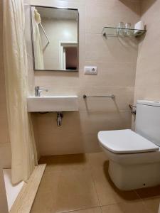 Un baño con inodoro, lavabo y espejo. en P&R hostals Maria Rosa, en Tossa de Mar