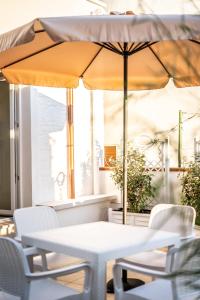 - une table et des chaises avec un parasol sur la terrasse dans l'établissement DIMORA PALASCIANO, à Alberobello