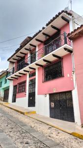 un edificio de color rosa y blanco con balcón en kukulkan hostal en San Cristóbal de Las Casas