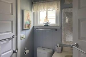 a bathroom with a toilet and a window with a boat on it at Peaceful Cottage By The Sea Oceanfront Home! in Surf City +28 photos